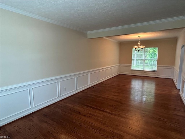 empty room featuring a chandelier, dark wood-style flooring, crown molding, a decorative wall, and a textured ceiling