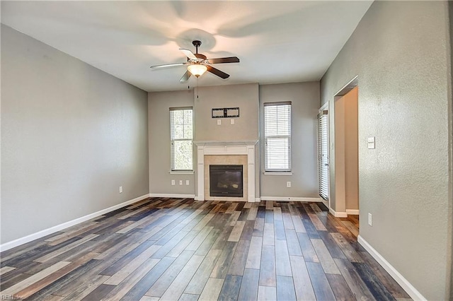 unfurnished living room with ceiling fan, dark wood-type flooring, a fireplace, and baseboards