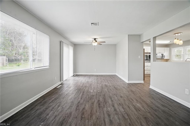unfurnished living room featuring a ceiling fan, dark wood-type flooring, and baseboards
