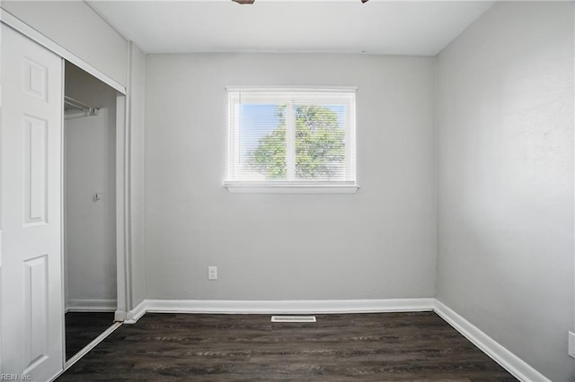 unfurnished bedroom with dark wood-type flooring, baseboards, and a closet