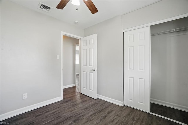 unfurnished bedroom featuring dark wood-style flooring, a closet, baseboards, and a ceiling fan