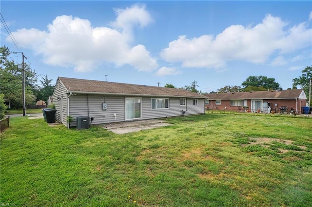 rear view of property featuring central air condition unit, a yard, and a patio area