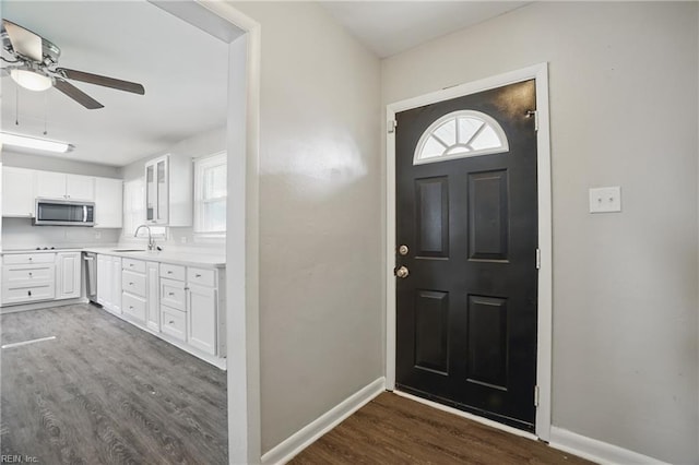 foyer entrance with dark wood-type flooring, ceiling fan, and baseboards