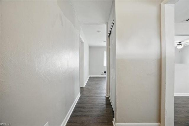 corridor with dark wood finished floors and baseboards