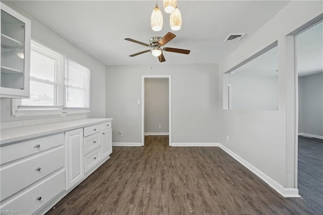 spare room with a ceiling fan, dark wood finished floors, and baseboards