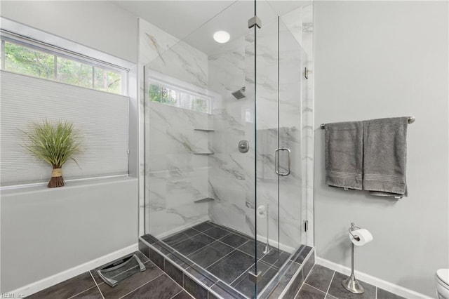 full bath with a marble finish shower, baseboards, and toilet