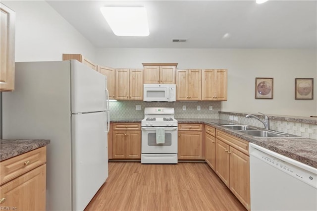 kitchen with white appliances, a sink, light brown cabinets, and light wood finished floors