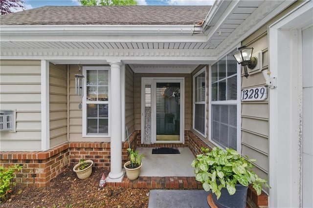 property entrance featuring a shingled roof and covered porch