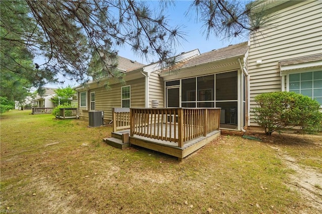 rear view of house with a deck, cooling unit, and a lawn