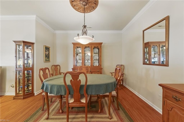 dining space with light wood-type flooring, baseboards, and ornamental molding