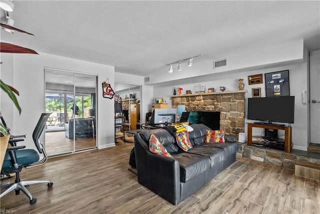 living area with wood finished floors, a textured ceiling, a desk, and track lighting
