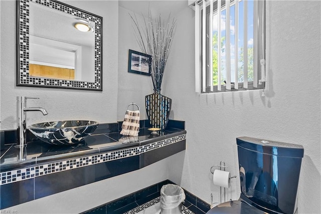 bathroom with a sink, a textured wall, and baseboards