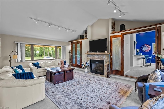 carpeted living room with rail lighting, vaulted ceiling, and a fireplace
