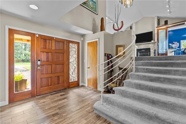 entryway featuring stairs, vaulted ceiling, wood finished floors, baseboards, and rail lighting