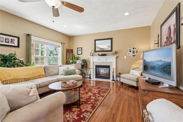 living room featuring ceiling fan, a fireplace with flush hearth, wood finished floors, and recessed lighting