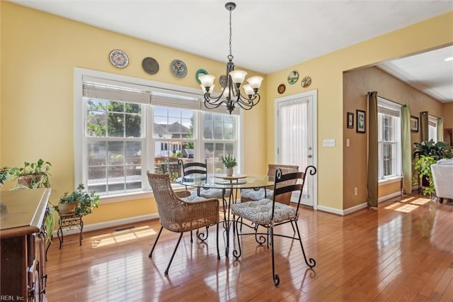 dining room with hardwood / wood-style flooring, a chandelier, and baseboards