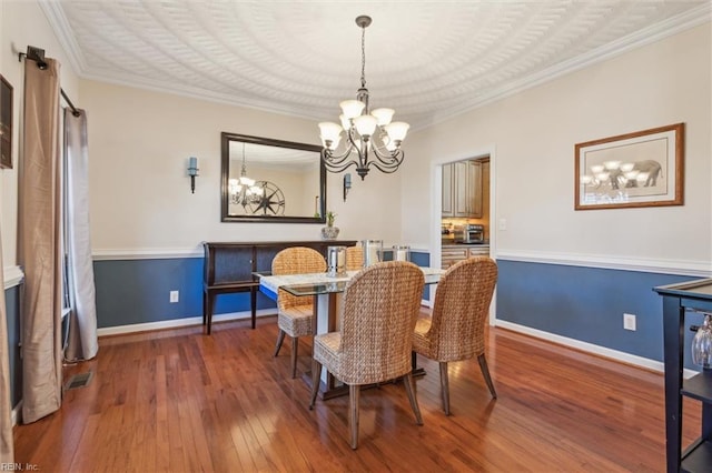 dining area with a chandelier, hardwood / wood-style flooring, baseboards, and crown molding