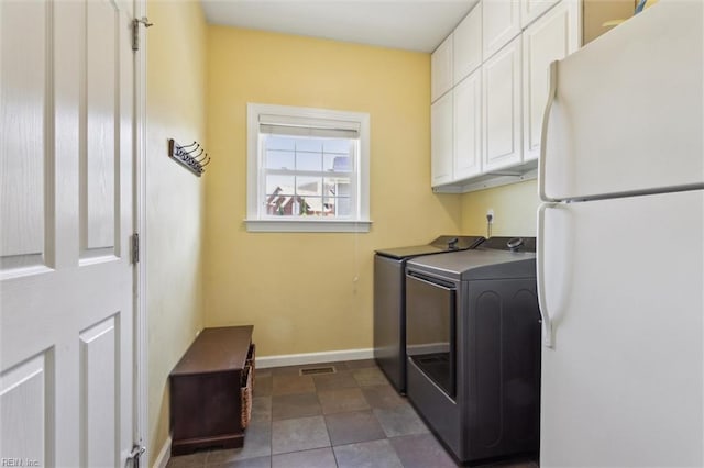 clothes washing area with separate washer and dryer, cabinet space, and baseboards