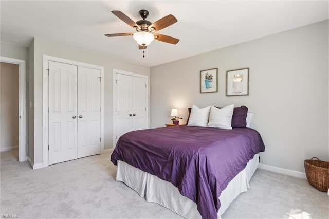 bedroom featuring light colored carpet, baseboards, two closets, and a ceiling fan