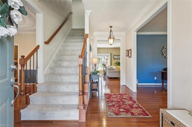entryway with wood finished floors, stairs, crown molding, and baseboards