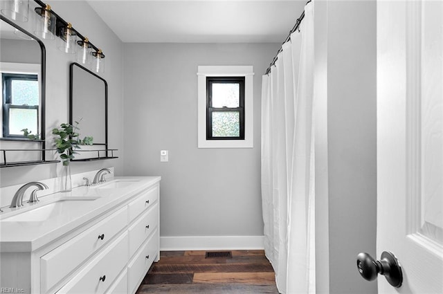 8209 Harlan Dr, Suffolk, VA 23436 - bathroom featuring wood finished floors, baseboards, and double vanity
