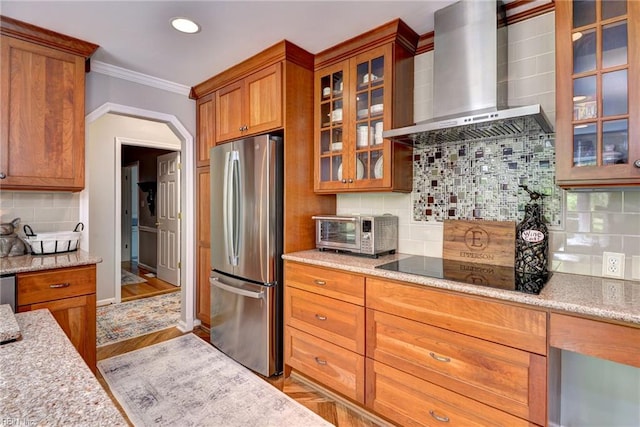 108 Devonshire Dr, Williamsburg, VA 23188 - kitchen featuring freestanding refrigerator, wall chimney exhaust hood, black electric stovetop, decorative backsplash, and brown cabinets
