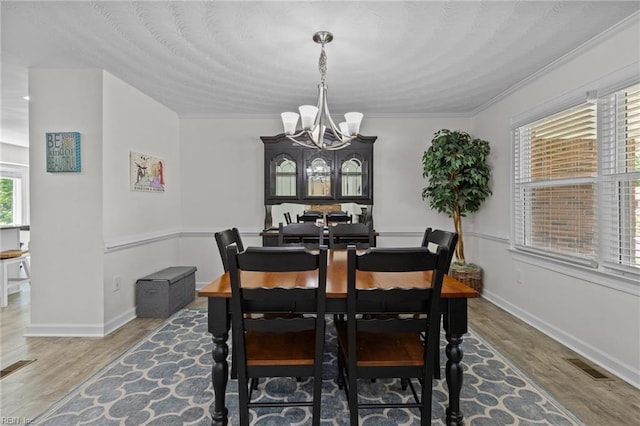 dining space featuring a chandelier, wood finished floors, crown molding, and baseboards