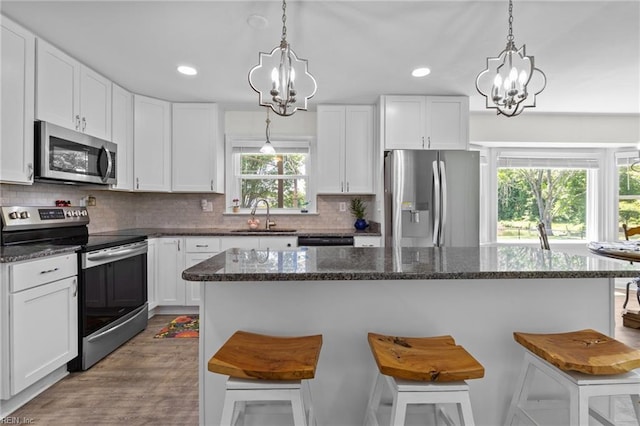 kitchen with stainless steel appliances, a chandelier, a sink, white cabinetry, and recessed lighting