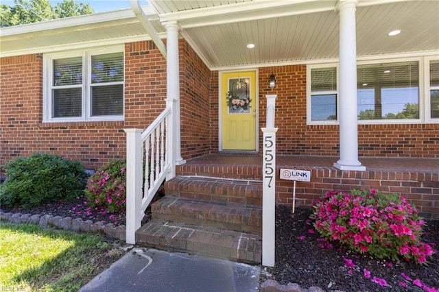 entrance to property with brick siding and a porch