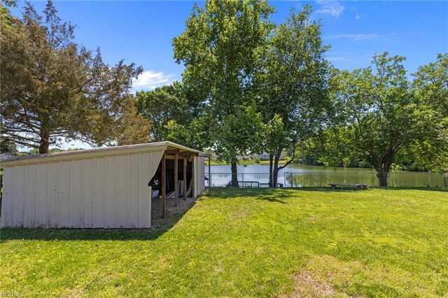view of yard with a water view, a pole building, and an outbuilding