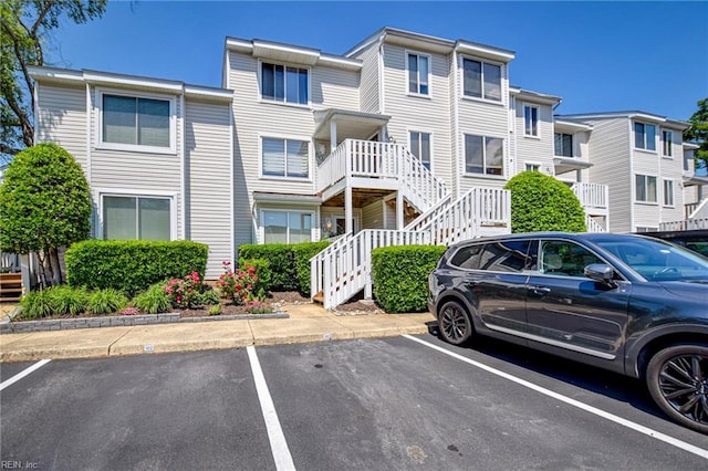 view of building exterior featuring stairs, uncovered parking, and a residential view