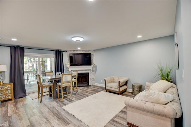 living room with a high end fireplace, light wood-style flooring, and recessed lighting