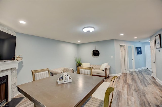 dining space featuring a high end fireplace, wood finished floors, recessed lighting, and baseboards