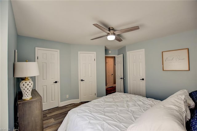 bedroom with wood finished floors, baseboards, a ceiling fan, and multiple closets