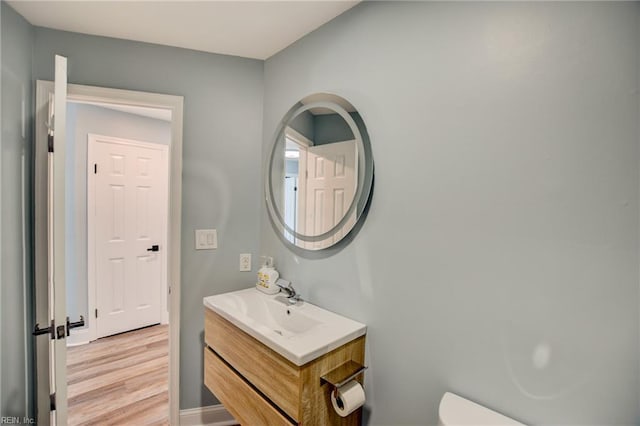 bathroom featuring toilet, vanity, wood finished floors, and baseboards