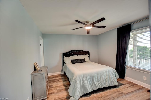 bedroom featuring light wood finished floors, baseboards, and a ceiling fan