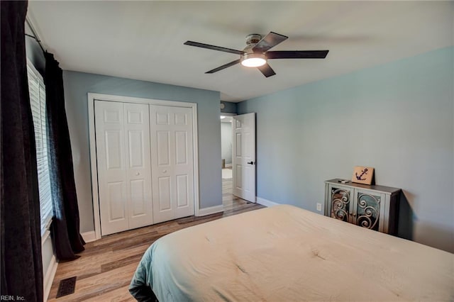 bedroom with wood finished floors, a closet, baseboards, and ceiling fan