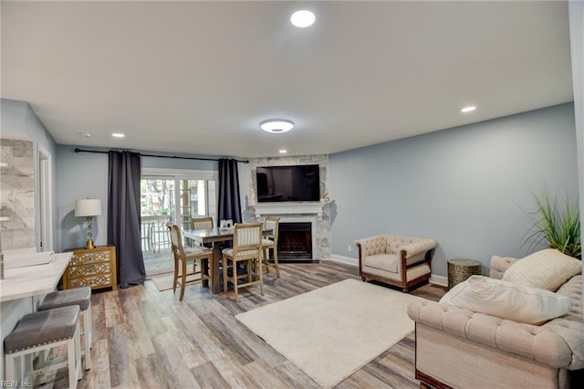 living area featuring a fireplace, light wood-type flooring, recessed lighting, and baseboards