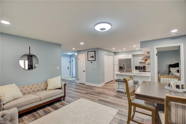 living room with light wood finished floors, baseboards, and recessed lighting