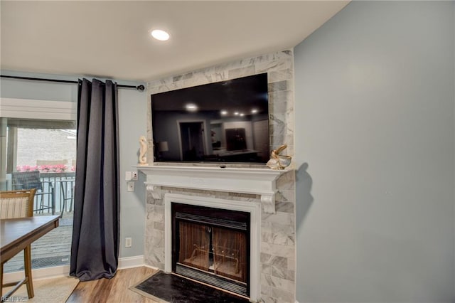 detailed view of wood finished floors, a large fireplace, and baseboards
