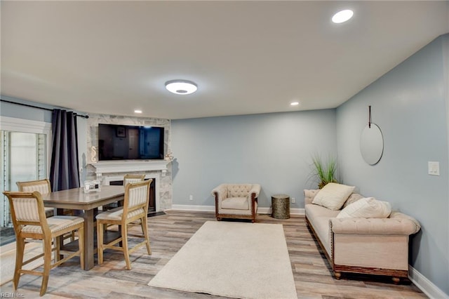 dining room featuring baseboards, light wood-style flooring, a fireplace, and recessed lighting