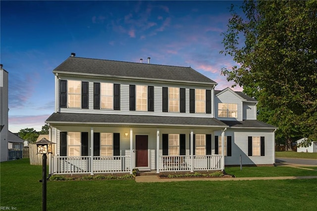 colonial home with a porch and a lawn