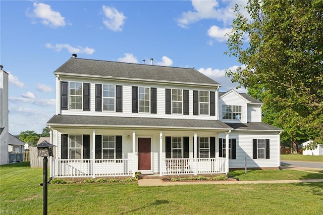 colonial house featuring covered porch and a front yard