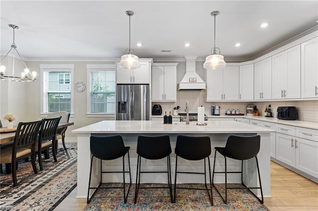 2349 Treesong Trl, Virginia Beach, VA 23456 - kitchen with stainless steel fridge with ice dispenser, custom exhaust hood, light wood-type flooring, a kitchen bar, and ornamental molding
