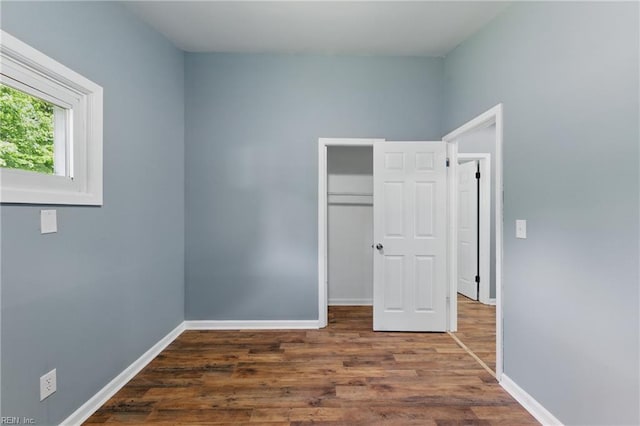 unfurnished bedroom with wood finished floors, baseboards, and a closet