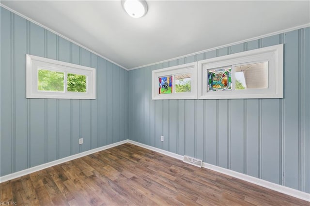 empty room featuring crown molding, dark wood finished floors, and baseboards