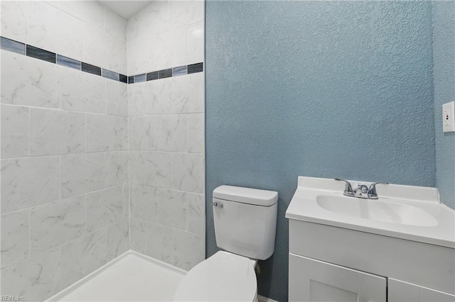 full bath with toilet, vanity, and tiled shower
