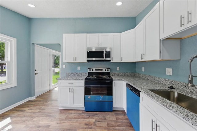 kitchen featuring stainless steel microwave, dishwashing machine, electric range, a sink, and plenty of natural light