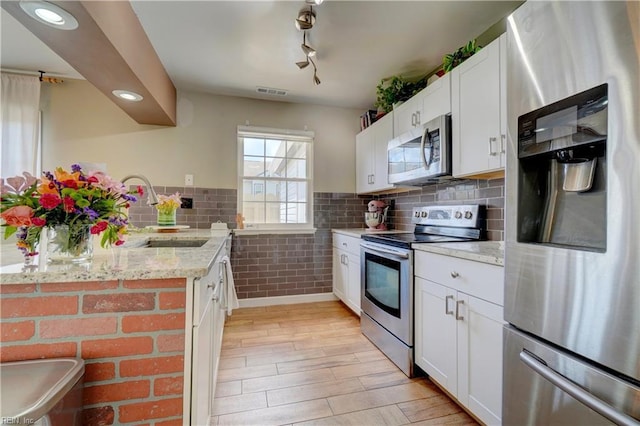 100 Castilian Dr, Virginia Beach, VA 23462 - kitchen with stainless steel appliances, a sink, light wood finished floors, light stone counters, and white cabinetry