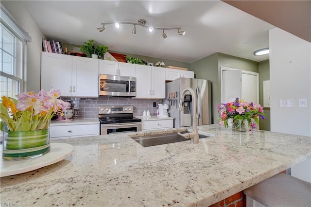 100 Castilian Dr, Virginia Beach, VA 23462 - kitchen featuring appliances with stainless steel finishes, a sink, white cabinets, decorative backsplash, and light stone countertops